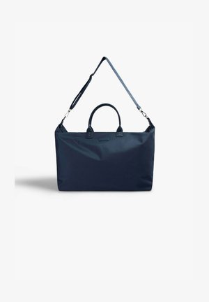Bolsa de viaje rectangular azul marino con dos asas cortas y una correa de hombro ajustable, sobre un fondo blanco.