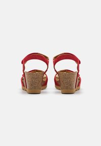 Sandales compensées en suède rouge avec un talon en liège texturé, dos ouvert, brides de cheville réglables et doublure intérieure lisse.