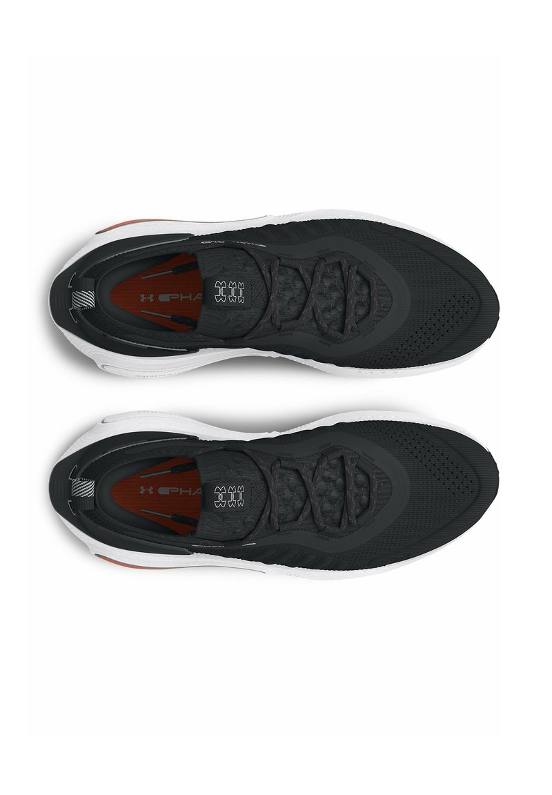 Une paire de baskets de sport noir et blanc avec un design à lacets, des semelles blanches rembourrées et des semelles intérieures rouges, montrées en vue de dessus sur fond blanc.