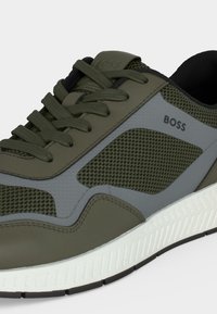 Baskets BOSS vert olive et gris avec tige en mesh et cuir, fermeture à lacets et semelle blanche texturée.
