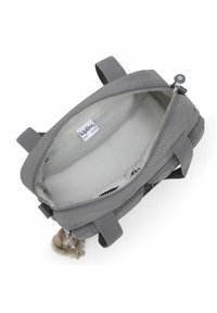 Bolsa gris con cremallera, interior suave, asas dobles y un colgante de llavero. El material parece durable con una textura suave.