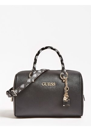 Sac à main noir Guess avec poignée et bandoulière blanches à motifs, logo doré et chaîne dorée décorative avec breloque en forme de cadenas sur fond blanc.