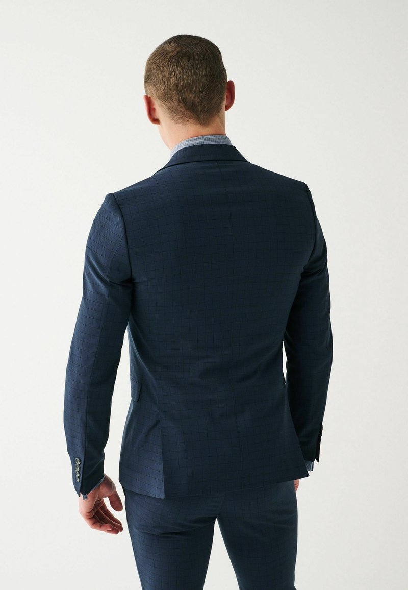Navyblauwe geruite blazer met een satijnen afwerking, voorzien van pieklapels, een enkele split en knoopmanchetten. Getailleerde pasvorm.