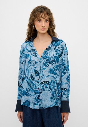 Camicia blu con motivo paisley e colletto in denim, dotata di chiusura a bottoni e maniche lunghe con polsini a contrasto. Texture liscia.