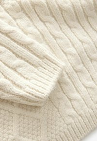 Pull en tricot à torsades épais de couleur crème, présentant de larges motifs torsadés et des poignets côtelés. Texture douce avec des motifs de points variés tout au long.