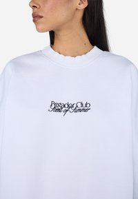 Witte sweatshirt met gegolfde halslijn en geborduurde tekst: "Pegador Club Scent of Summer" in het zwart, met een klassieke, relaxte pasvorm.