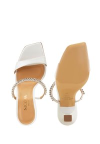 Witte blokhakken sandalen met een vierkante neus, voorzien van een brede band en een enkelbandje met strass. Glad leer en rubberen zool.