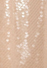 Tejido nude con lentejuelas redondas superpuestas y brillantes de diferentes tamaños, creando una superficie texturizada y reflectante.