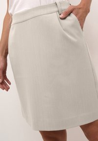 Jupe gris clair, longueur genoux, fabriquée en tissu texturé avec des rayures verticales, dotée d'une poche latérale et d'une taille plate.