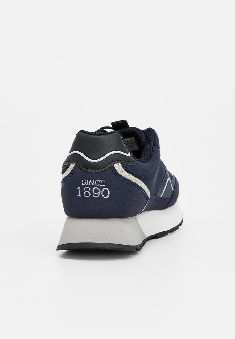 Zapatilla azul marino con parte superior de textil suave, acentos grises, un logotipo blanco y una suela acolchada con un patrón texturizado.