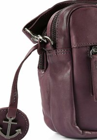 Ledrige Umhängetasche in Dunkellila mit glatter Oberfläche, ausgestattet mit einem Reißverschluss und einem Metall-Anker-Schlüsselanhänger als Akzent.