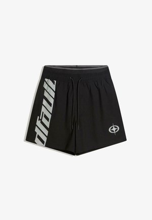 Schwarze sportliche Shorts mit elastischem Bund und Kordelzug, mit großem vertikalem reflektierendem Text am linken Bein und rundem Logo am rechten Bein.