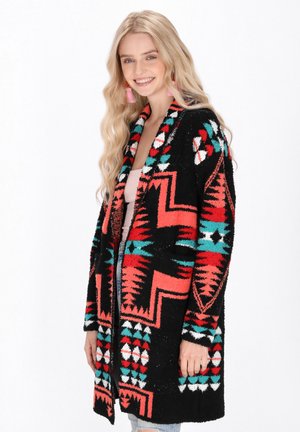 Schwarze Strickjacke mit bunten geometrischen Mustern in Rot, Petrol und Weiß. Weicher Stoff, offen gestaltetes Design und lange Ärmel.