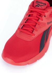 Scarpa sportiva rossa con tomaia in mesh, accenti in pelle sintetica, logo nero e chiusura con lacci. Superficie testurizzata e suola ammortizzata visibili.
