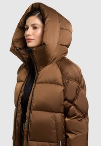 Braune Steppjacke mit großer Kapuze, gesteppter Optik und Reißverschluss. Gefertigt aus glattem Stoff, ideal zum Lagenlook.