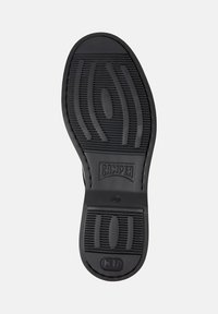 Talpă de pantof neagră cu un model texturat pentru aderență, logo "CAMPER", mărimea 42, și un simbol cu textul "EXTRALIGHT" aproape de călcâi.