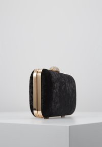 Černé sametové psaníčko obdéln íkového tvaru se zlatým kováním a zdobenou sponou. Hladká textura s minimalistickými designovými detaily.