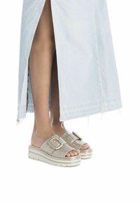 Geweven metalen sandalen met een brede band en een oversized gesp. Lichtgekleurde zool met een lichte plateau en een textuur bovenkant.