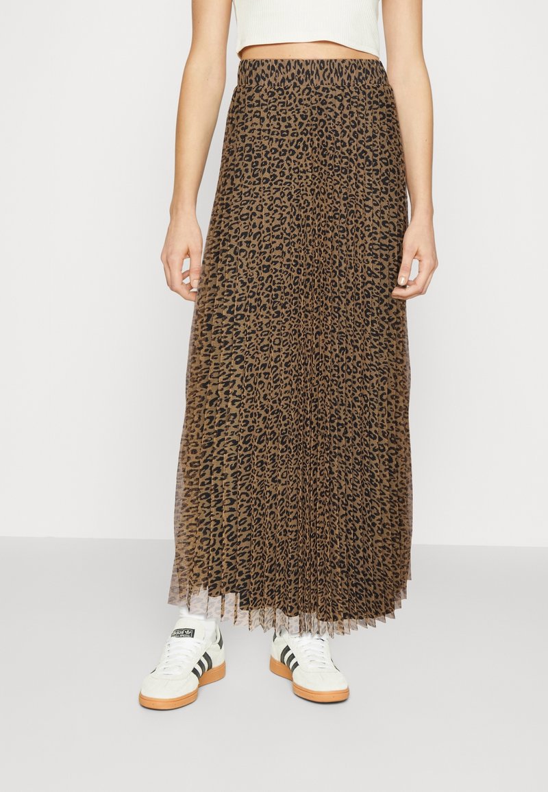 Jupe maxi à imprimé léopard avec un design plissé et une taille élastique, fabriquée dans un matériau léger ; associée à des baskets blanches avec des accents noirs.