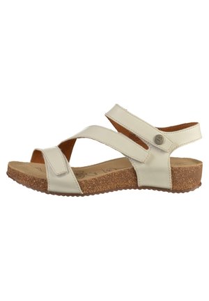 Hvid lædersandal med justerbare remme og korksål, med flad bund og en knapdetalje nær ankelremmen.