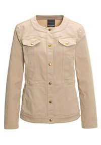 Beige spijkerjas met twee borstzakken, gouden hardware en een licht getailleerd ontwerp. Heeft een ronde halslijn en drukknoopsluiting.