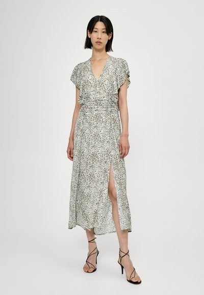 Vestito a portafoglio floreale nei colori bianco, verde e marrone, con maniche corte, scollo a V profondo e uno spacco alto fino all coscia. Tacchi neri con cinturini.