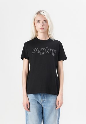 Svart bomull t-skjorte med "replay" logo i hvitt på brystet. Korte ermer og en avslappet passform, sammen med lyseblå jeans.