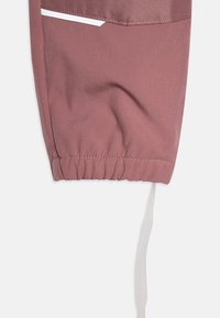 Dusty rose trenerice s elastičnom manžetom i kontrastnom bijelom vezicom. Glatkoga, laganog materijala s suptilnom teksturom.
