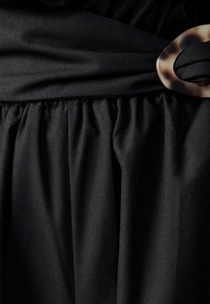 Czarna tkanina o miękkiej strukturze, z marszczoną talią i dużą, przezroczystą klamrą w stylu żółwiowym jako akcentem.
