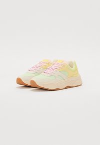 Sneakers con una toma superior in rete di colore verde chiaro, giallo e beige. Presentano lacci rosa e una suola in gomma gommata textured. Design della punta arrotondata.