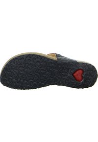 Black rubber sole with textured floral pattern, light-colored midsole, featuring a red heart-shaped detail. Smooth leather upper visible.