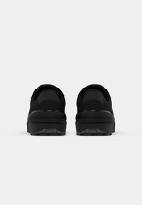 Black athletic shoes featuring a smooth, textured upper and cushioned sole, showing a round heel and distinctive tread pattern on the outsole.