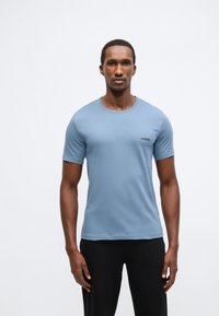 Šviesiai mėlyna trumpomis rankovėmis palaidinė su apvalia iškirpte ir maža juoda „HUGO“ logotipu kairėje krūtinės pusėje, pagaminta iš minkštos, tekstūruotos medžiagos.