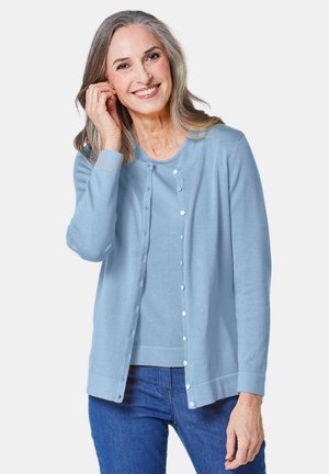 Hellblauer Cardigan aus weichem Stoff mit Rundhalsausschnitt, Knopfleiste und gerippten Bündchen. Über einem passenden Oberteil getragen.
