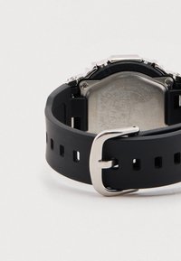 Mustast kummist rihmaga digikell roostevabast terasest tagaküljega, hõbedase pandla ja mitme reguleerimiskohaga.