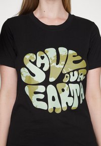 T-shirt de algodão preta com um design "Salvem a Nossa Terra". A letra é verde-clara com um padrão texturizado em tons de terra, enfatizando a conscientização ambiental.