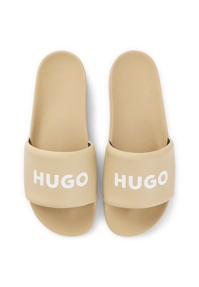 Бежови слайд сандали с релефни стелки и широки каишки с бялото лого HUGO отпред.