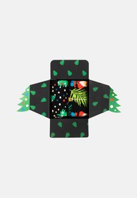 Svart presentlåda formad som en julgran, som innehåller två par strumpor. Det ena har en färgglad palmlövsdesign; det andra har prickar.