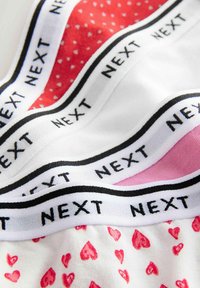 Fyra par underkläder i färgerna vit, rosa och röd, med en midjeband i svart med texten "NEXT" och hjärt-mönster på ett par.