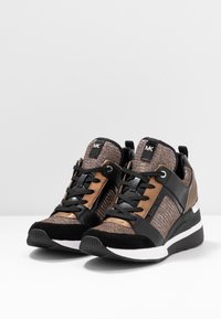 Schwarze und bronzefarbene Sneakers mit einer strukturierten Oberseite, Wildlederakzenten und einer runden Zehenpartie. Sie verfügen über eine dicke weiße Sohle und schwarze Schnürsenkel.