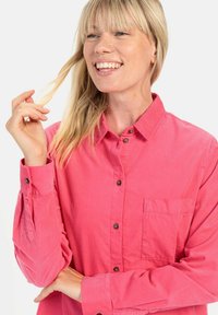 Roze corduroy overhemd met lange mouwen, voorzien van een borstzak en bruine knopen. Soepele textuur en een ontspannen pasvorm.