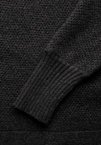 Schwarzer gestrickter Pullover mit einem strukturierten Muster und gerippten Bündchen. Das Material wirkt weich und warm, mit einer einheitlichen dunklen Farbe.