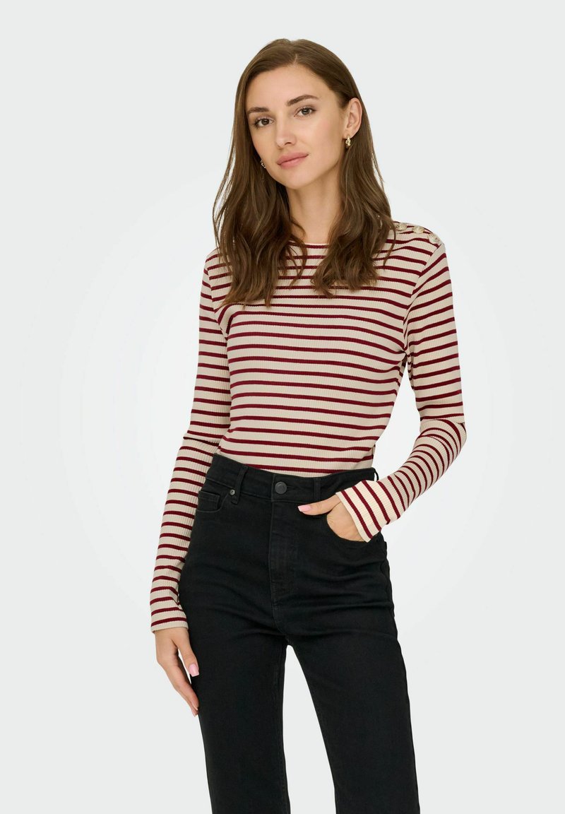 Gestreept langarmshirt in crème en bordeaux, met een aansluitend ontwerp, ribbelstructuur en een ronde hals, gecombineerd met zwarte high-waisted jeans.