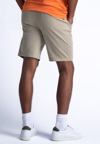Beige short met een lichtgewicht stof en zijzakken, gedragen met witte sneakers en geribbelde sokken, met een eenvoudige stijl en een relaxte pasvorm.