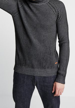 Schwarz- und grau gestreifter Pullover mit ribbelt Struktur, Rollkragen-Design und orangefarbenem Akzentetikett am Saum. Lange Ärmel mit eng anliegenden Manschetten.