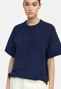 Granatowy sweter z krótkim rękawem o fakturowanym splocie. Posiada okrągły dekolt oraz luźny krój, wykonany z miękkiego, ciepłego materiału.