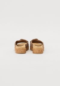 Brown slip-on sandals with cork soles. Soft upper material, open back design, and subtle stitching details. Comfortable footbed for support.