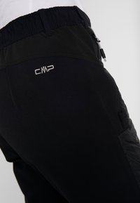 Pantaloni sportivi neri con pannello laterale testurizzato, elastico in vita e logo CMP ricamato sulla parte superiore. Dotati di tasche con zip.