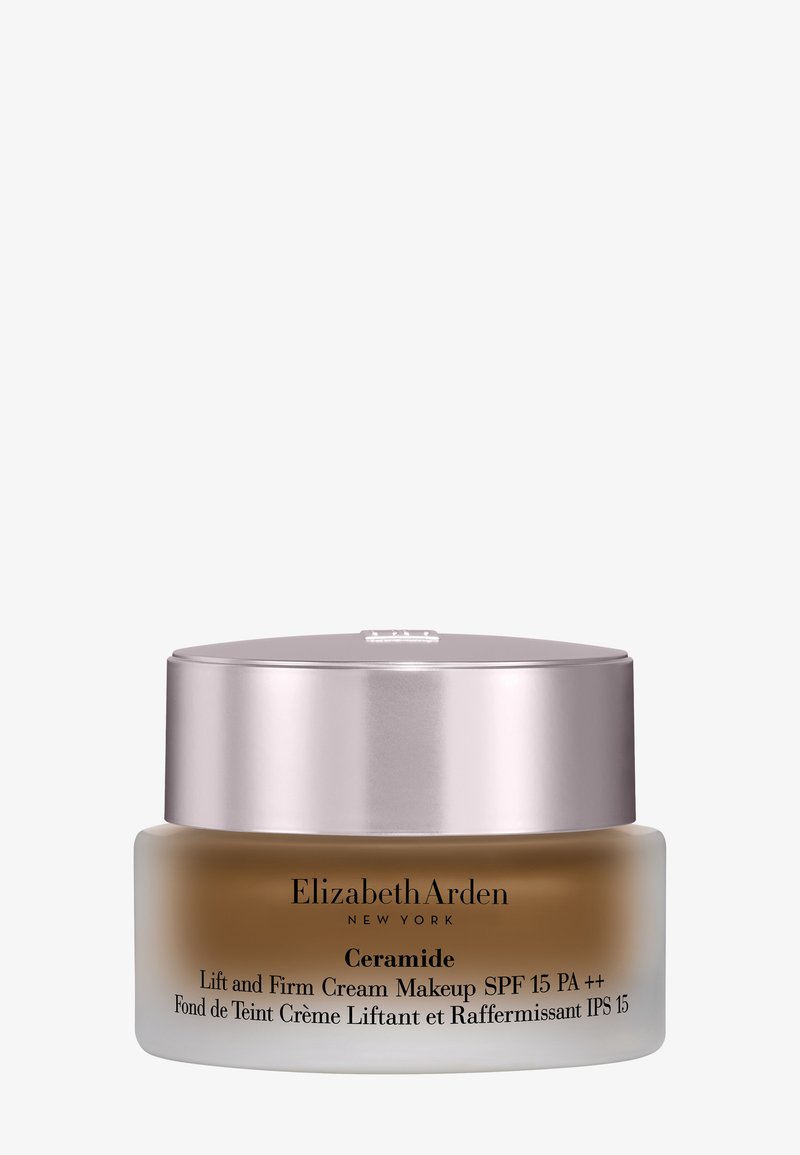 Tarro de maquillaje con crema de ceramida, con base de vidrio esmerilado, tapa metálica plateada y texto negro que detalla el nombre del producto y SPF.