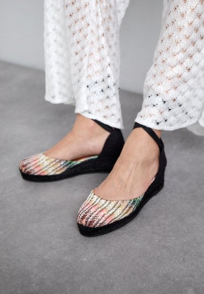 Saboți cu toc wedge, cu un superior din material texturat multicolor în nuanțe de roz, verde și auriu, și un fund și o curea din plasă neagră.